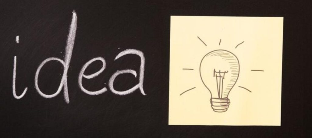 黑底上用粉笔写着‘idea’,旁贴画有灯泡的便签,象征广告创意构思中灵感迸发、创意生成的过程。